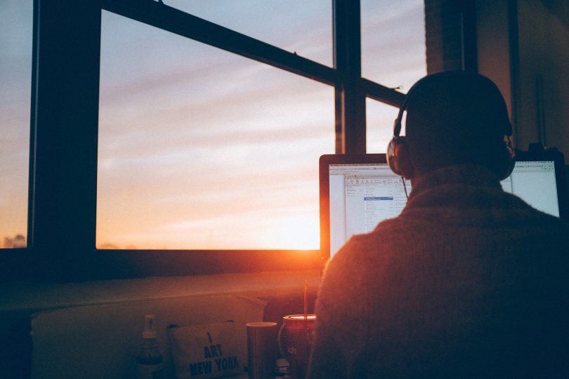 Homme devant ordinateur et couché de soleil